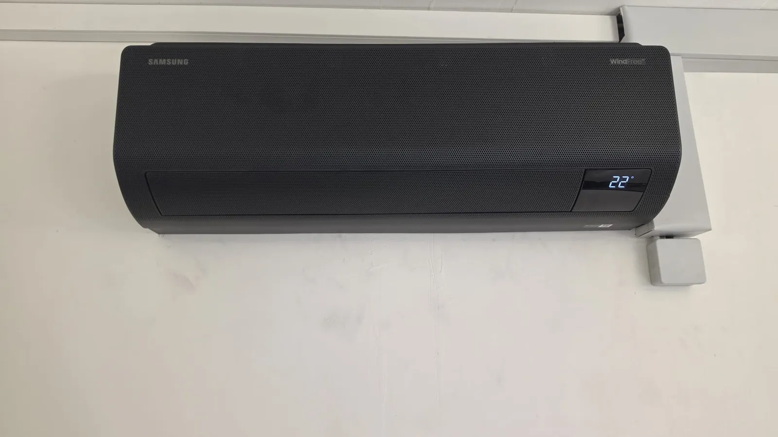 Innengerät einer von Strompartner installierten Split-Klimaanlage an einer weissen Wand, Display zeigt 22 Grad