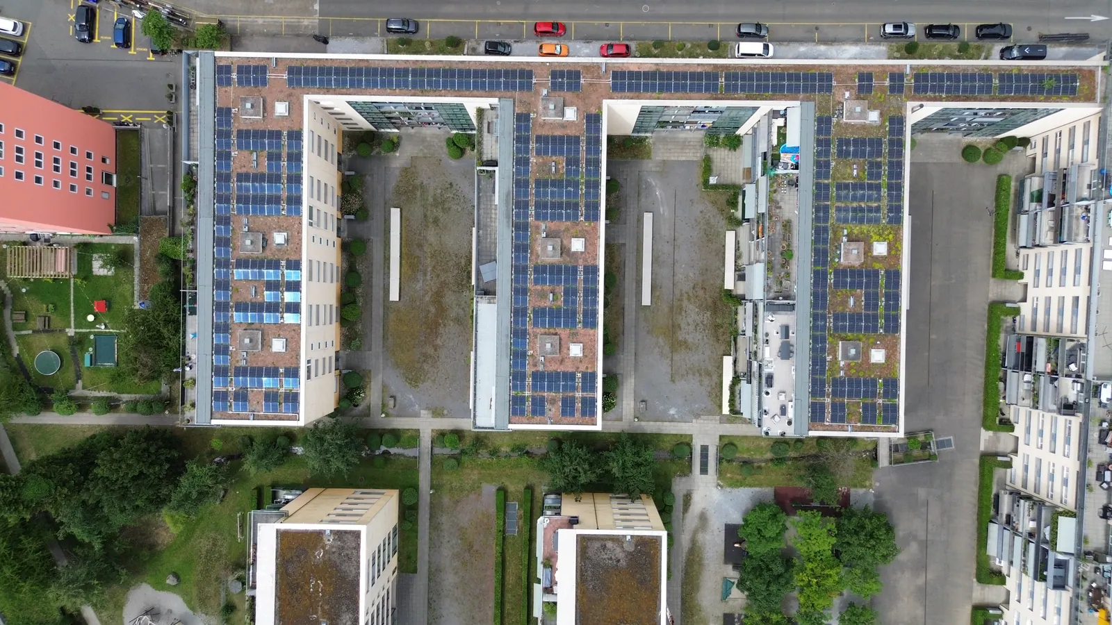 Drohnenaufnahme von oben: parallele Gebäudezeilen mit Photovoltaik auf den Dächern